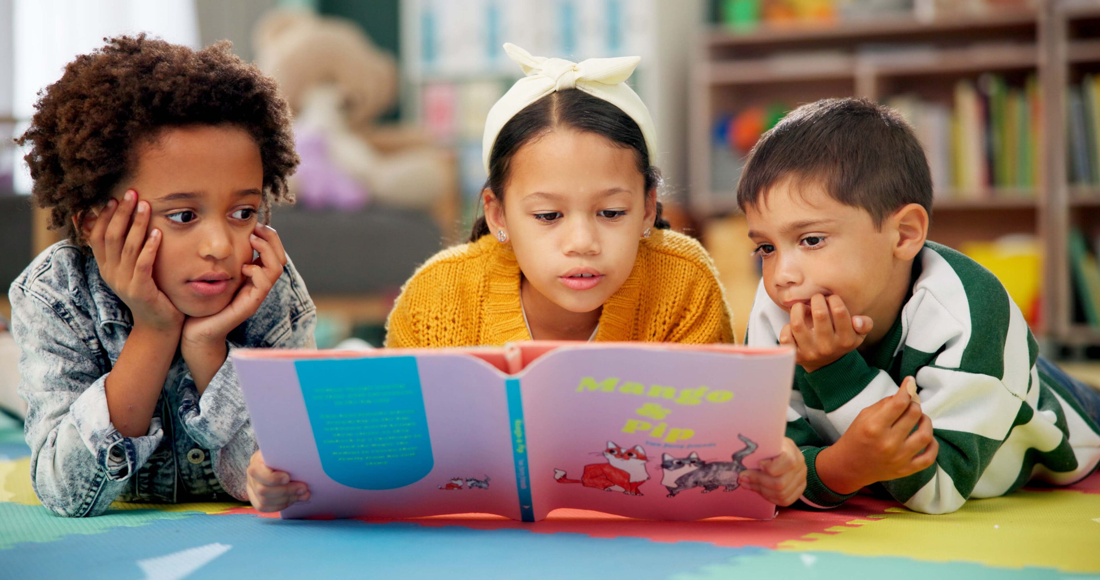 Three children are reading a book together.