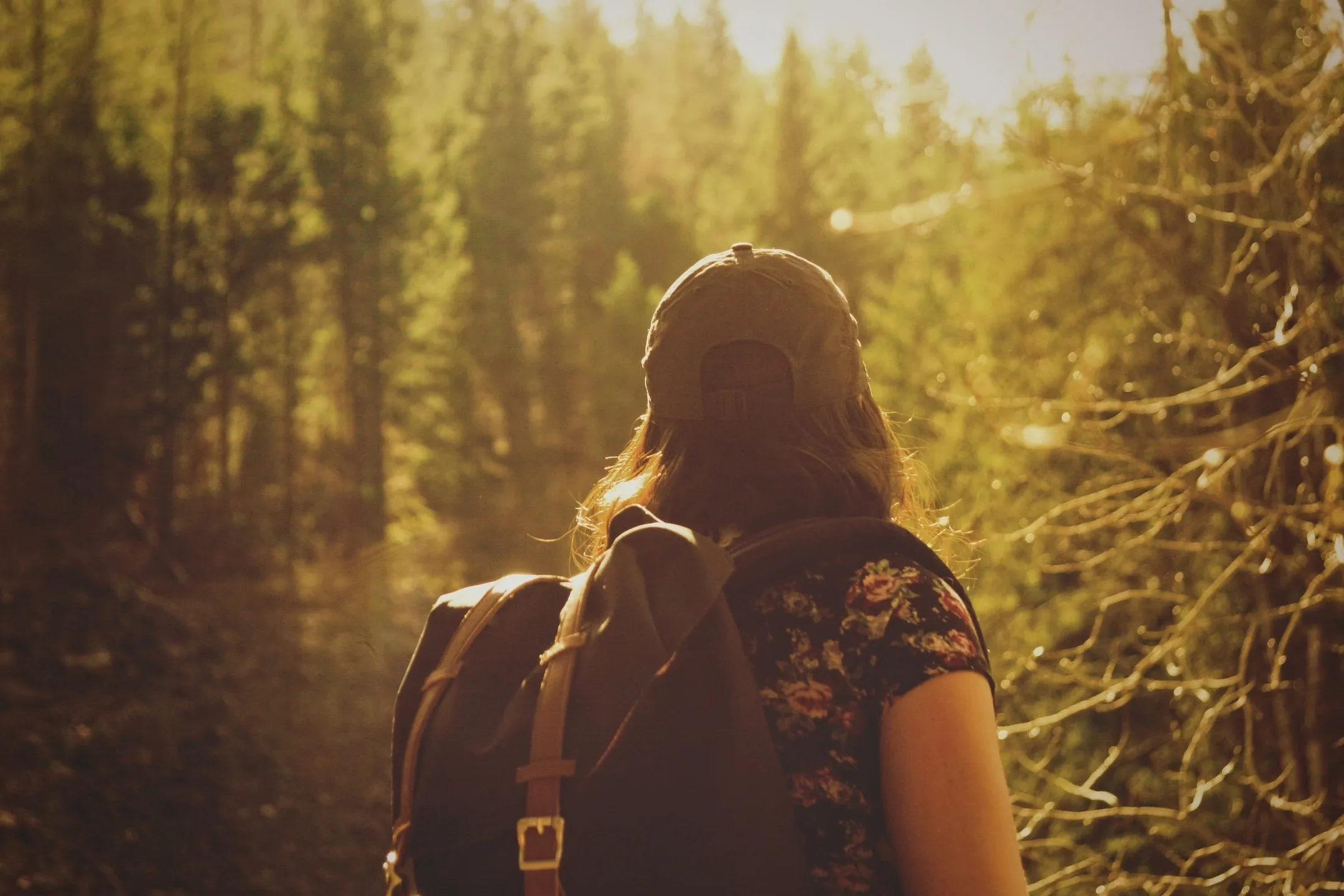 A woman with a backpack walking through the woods.