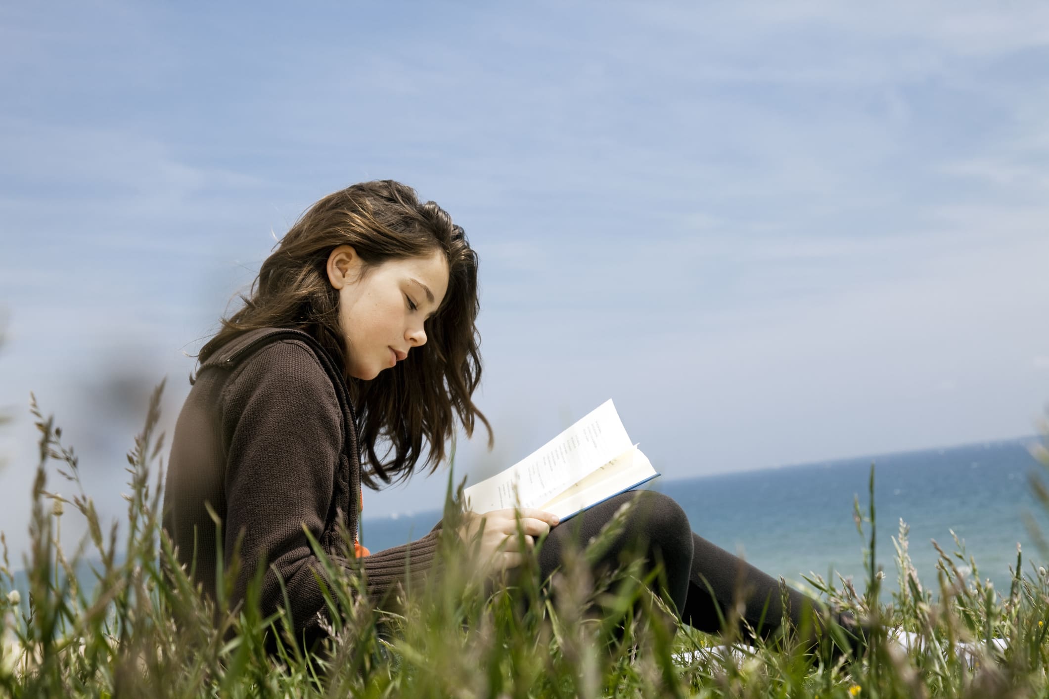Thirteen yars old reading poetry on a cliff.