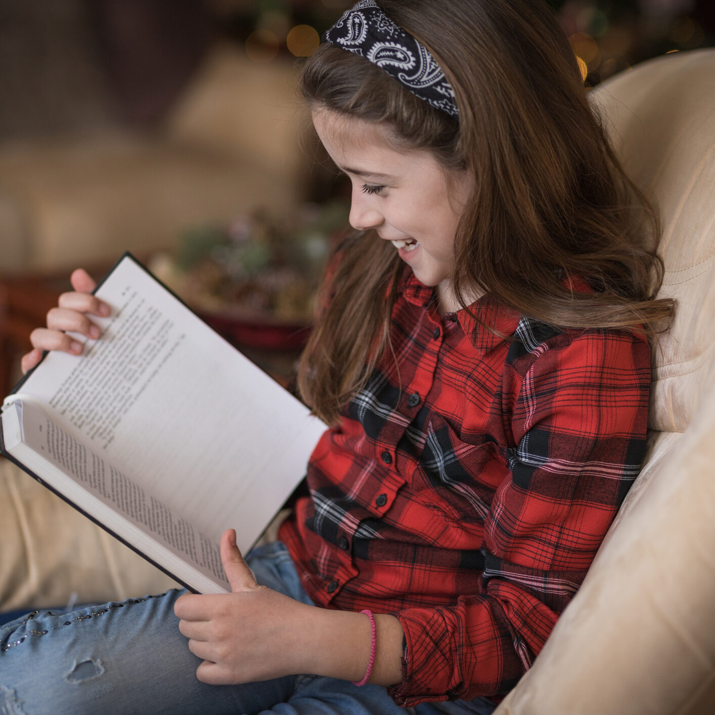 Girl laughing when reading a book Young happy girl reading a funny book and smiling