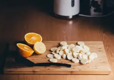 A cutting board with sliced bananas and oranges on it.