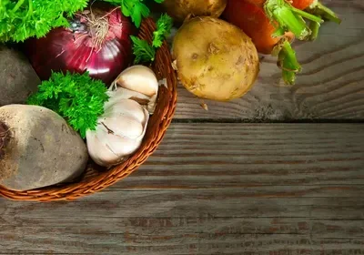 A basket of vegetables on top of a wooden table.